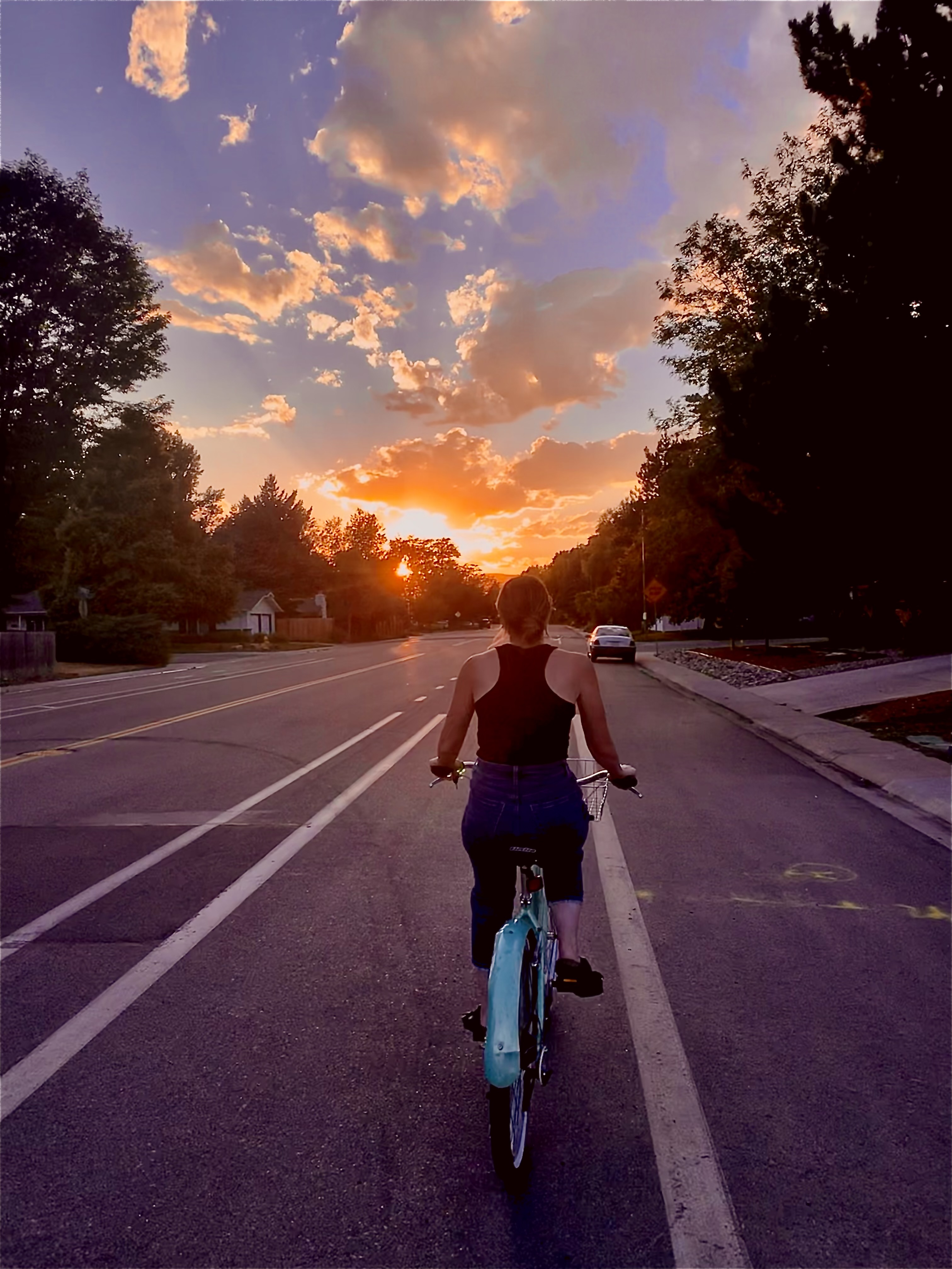 Woman riding a vintage blue bicycle at sunset, symbolizing conscious living, presence, and moving through life with intention.