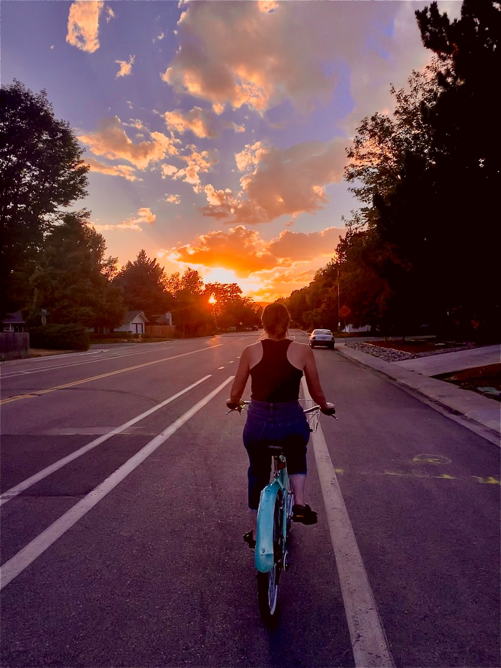 Woman riding a vintage blue bicycle at sunset, symbolizing conscious living, presence, and moving through life with intention.