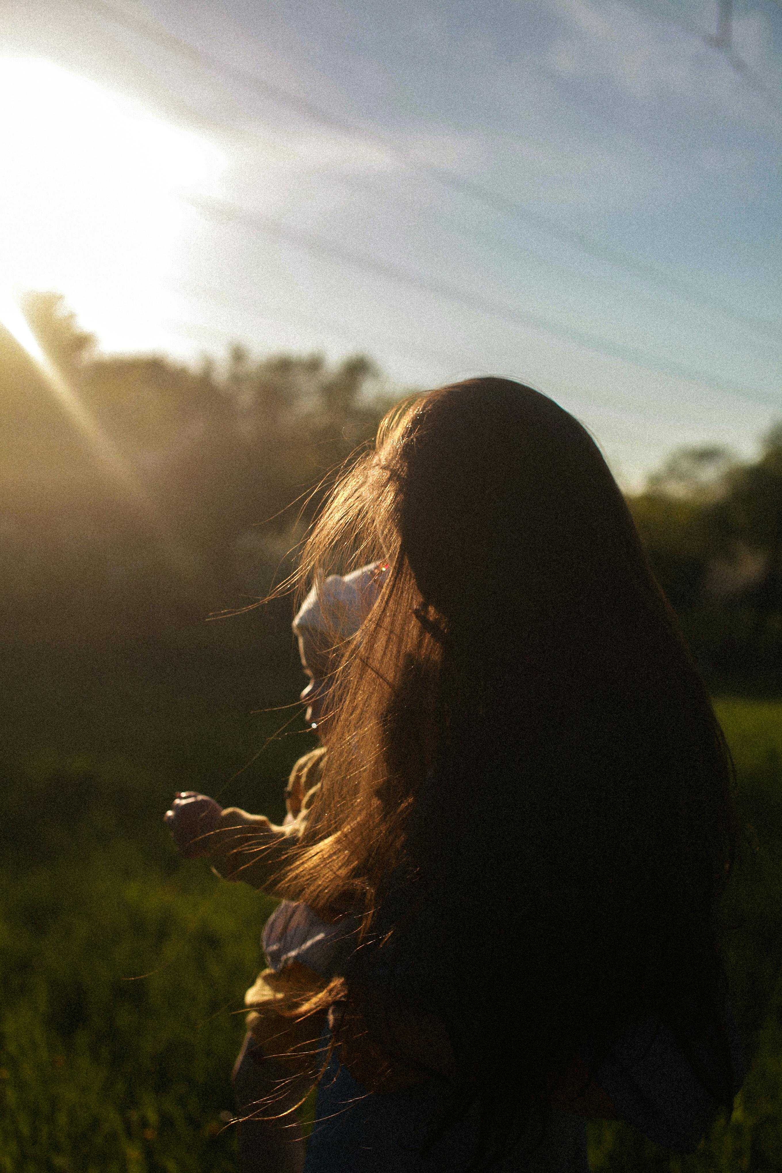 Woman standing in sunlight, reflecting on identity, personal growth, and the transformation of motherhood.